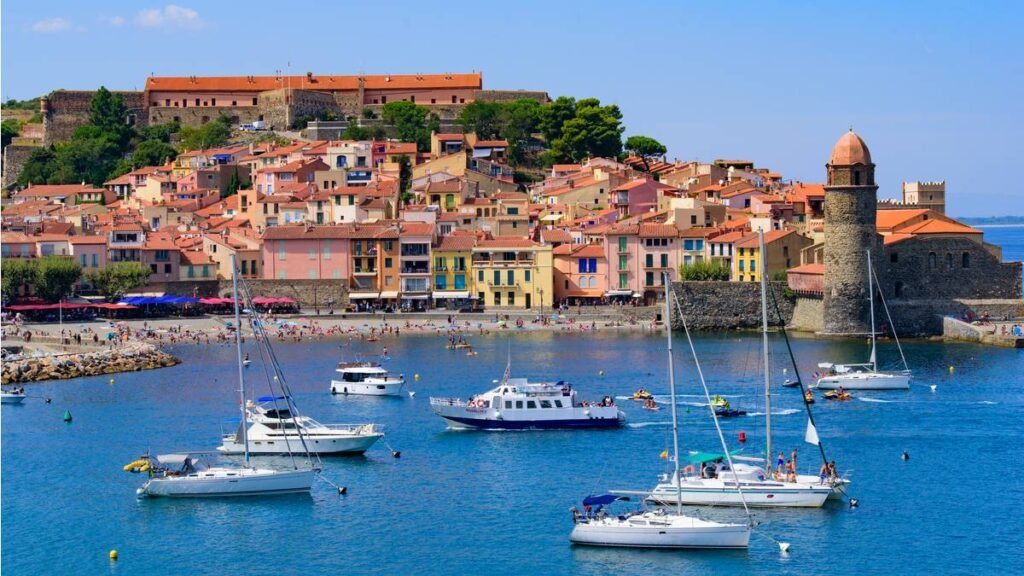 Village de Collioure photographié depuis la baie, on y voit des bateaux au premier plan puis l'église Notre Dame des Anges et le village de pêcheurs