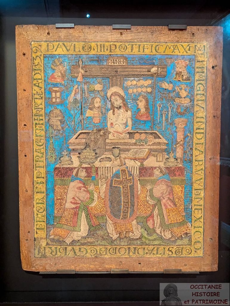Une mosaïque en plumes du XVIe siècle représentant le Christ dans le tombeau, flanqué de personnages agenouillés, entouré de symboles de la Passion et d'un texte en latin.